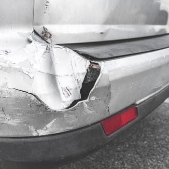 Damaged car. Road accident. Back of gray car get damaged from accident on the road. Vehicle bumper dent  broken by car crash. Retro style photo.