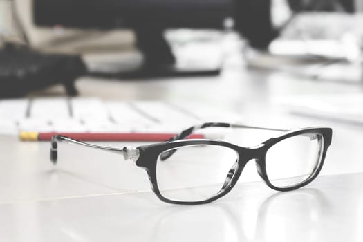 Glasses on the desk in an office. Blurred background. Ideal for Business and finance concept of office working.