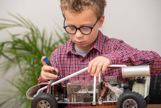 a little boy repairing a model radio-controlled car at home
