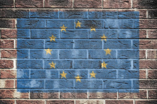 A European Union flag on brick wall background.