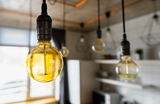Close-up of incandescent light bulbs hanging in modern kitchen. Decorative antique edison light bulbs with straight wire. Inefficient filament light bulbs waste electricity. Warm white, dimmable, E27