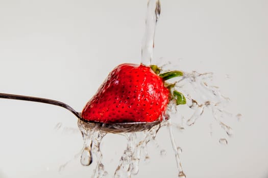 Strawberry on a spoon, being washed