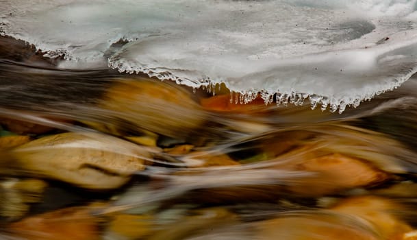 Background texture of river running swiftly under growing shelf of ice