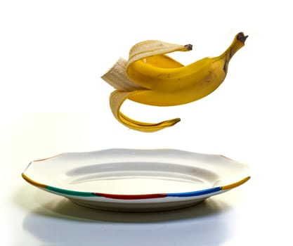 A peeled banana suspended midair over a plate