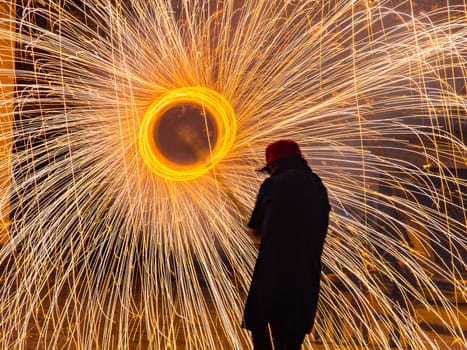 This man is holding a 6 foot pole with spinning fireworks on the end. He ducks his head to avoid sparks on his face in Cuenca, Ecuador