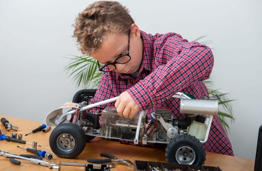 a little boy repairing a model radio-controlled car at home