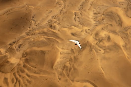 An ultralight aircraft can be seen flying over the sands of Namibia