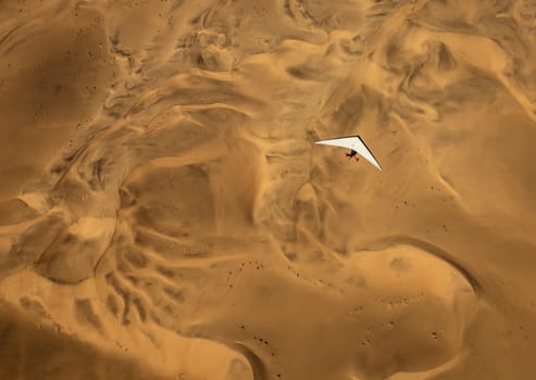 An ultralight aircraft can be seen flying over the sands of Namibia