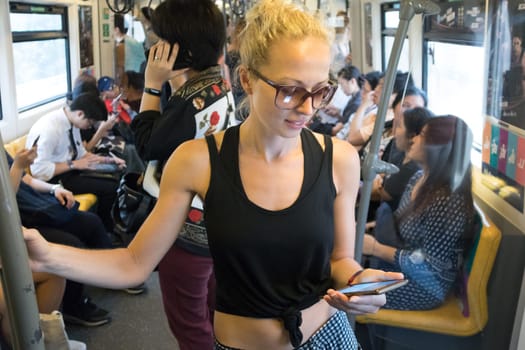 Caucasian female traveler using mobile phone on public transport metro in Kuala Lumpur,capital of Malaysia.