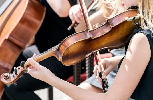 hands of the young woman violinist play music at concert