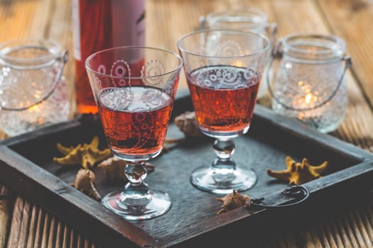 Two vintage glasses of red wine with bottle and lantern on wooden background