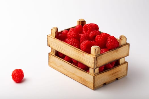 Some raspberries in a small wooden box on a white background