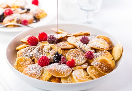 Poffertjes - small Dutch pancakes with fresh raspberries. Traditional Dutch cuisine.