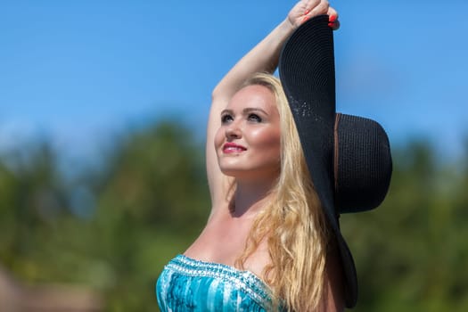 young blonde woman with a black hat on the beach of maldives