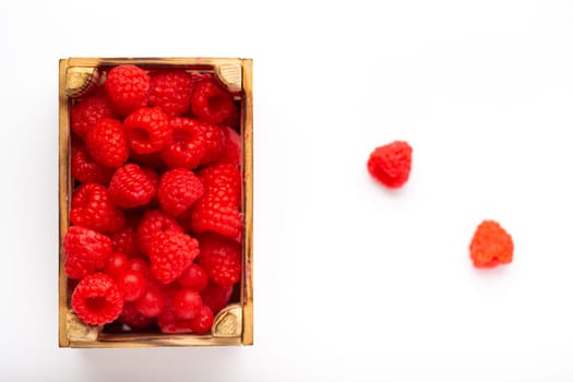 Some raspberries in a small wooden box on a white background