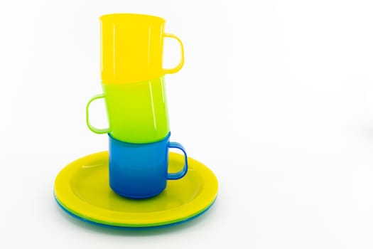 The three colored mugs and three colored saucers on a white background