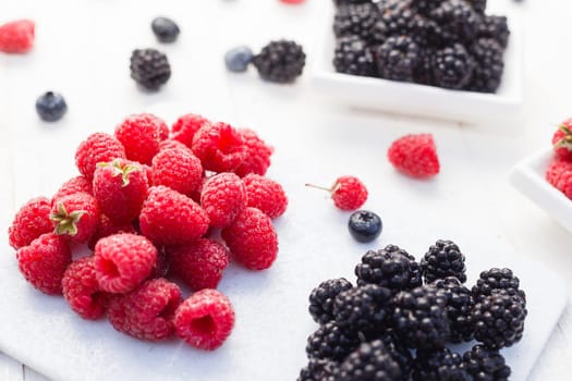 Blueberries, raspberries and blackberries on white background.