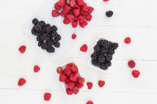 raspberries and blackberries white wooden background.