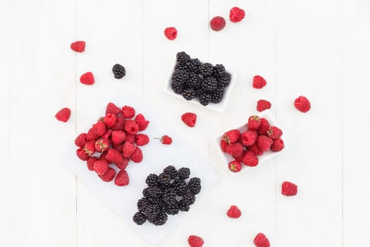 raspberries and blackberries white wooden background.