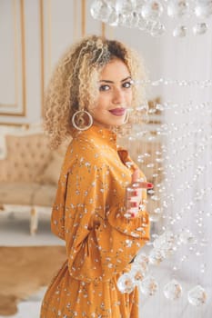 Luxury african mixed girl in fashionable dress posing near crystal chandelier in interior