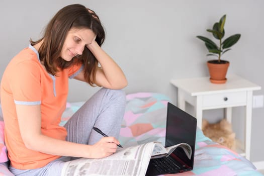 Girl browsing a newspaper at home and looking for job ads