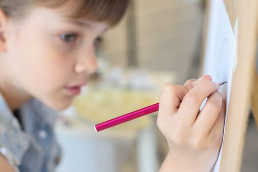 close-up of the hand of a girl drawing a pencil on an easel