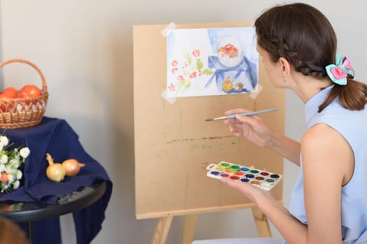 Girl paints watercolor still life with nature