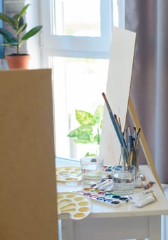 artist's workplace with easel, brushes and paints