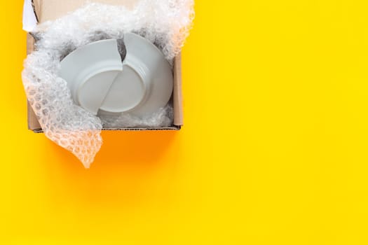 On a yellow background lies an open package, a box with a broken plate