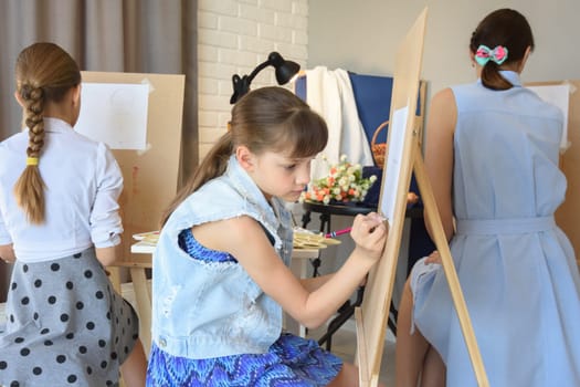 Children are engaged in an art studio with an artist