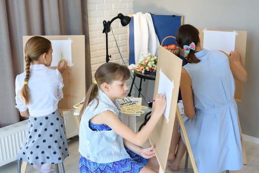 classes in the art studio behind the easels of children and adults