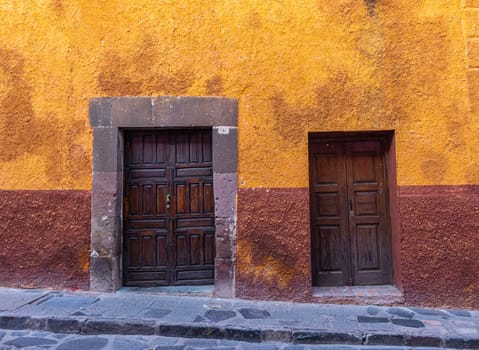 Colorful Wall with two wooden doors in the small streets, traditional of the historic town of San Miguel de Allende, Guanajuato, Mexico