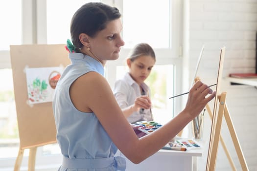 Artist teaches children to draw on an easel in the studio