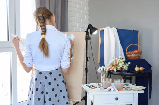 Young artist standing draws behind the easel still life from nature