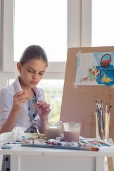 Girl examines brush for drawing watercolor paints