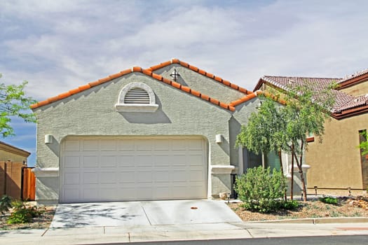 New one-story ranch, moss green and burnt orange stucco home in Tucson, Arizona, USA with beautiful blue sky and landscaping.