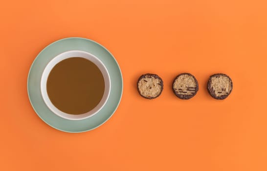 Chocolate bowl on a green light plate and three cookies. Orange background. Copy space
