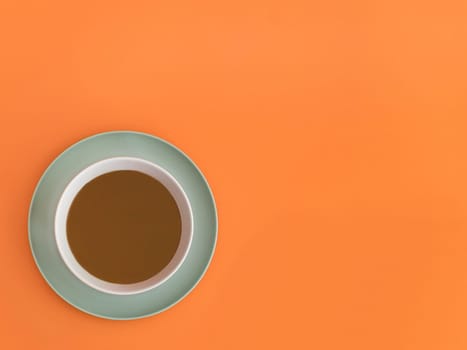 Chocolate bowl on a green light plate. Orange background. Copy space.