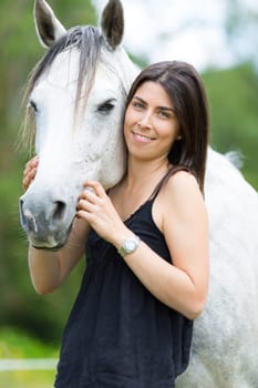 Happy young woman with her horse and strolling