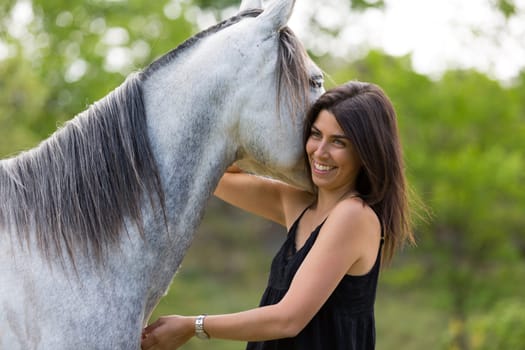 Happy young woman with her horse and strolling