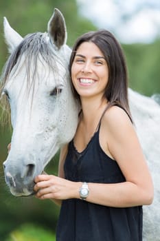 Happy young woman with her horse and strolling