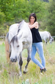 Happy young woman with her horse and strolling
