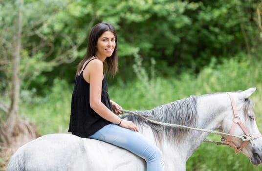 Happy young woman with her horse and strolling