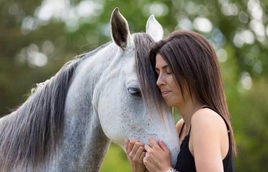 Happy young woman with her horse and strolling