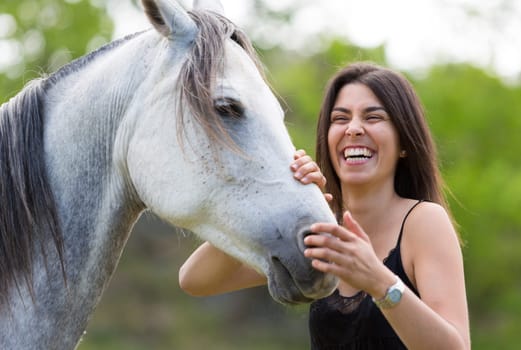 Happy young woman with her horse and strolling