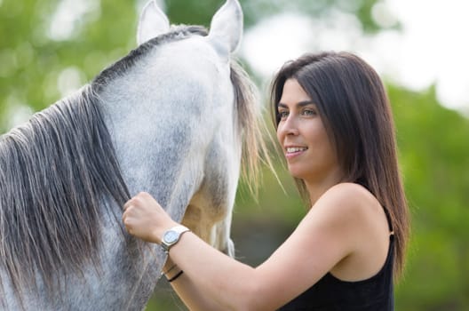 Happy young woman with her horse and strolling