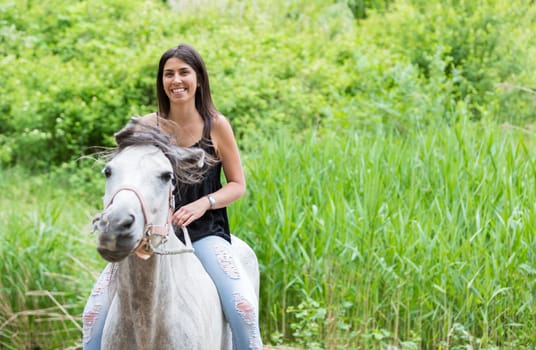 Happy young woman with her horse and strolling