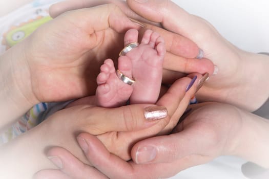 The Hands of adults hold small baby feet