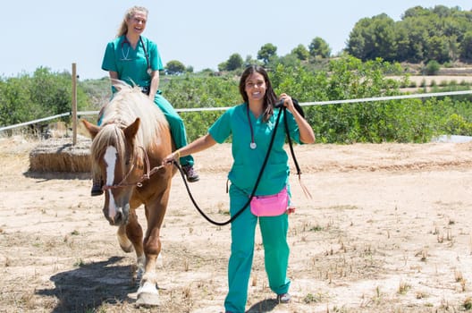Two young veterinary mounted on horseback at the farm