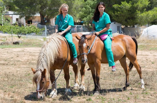 Two young veterinary mounted on horseback at the farm